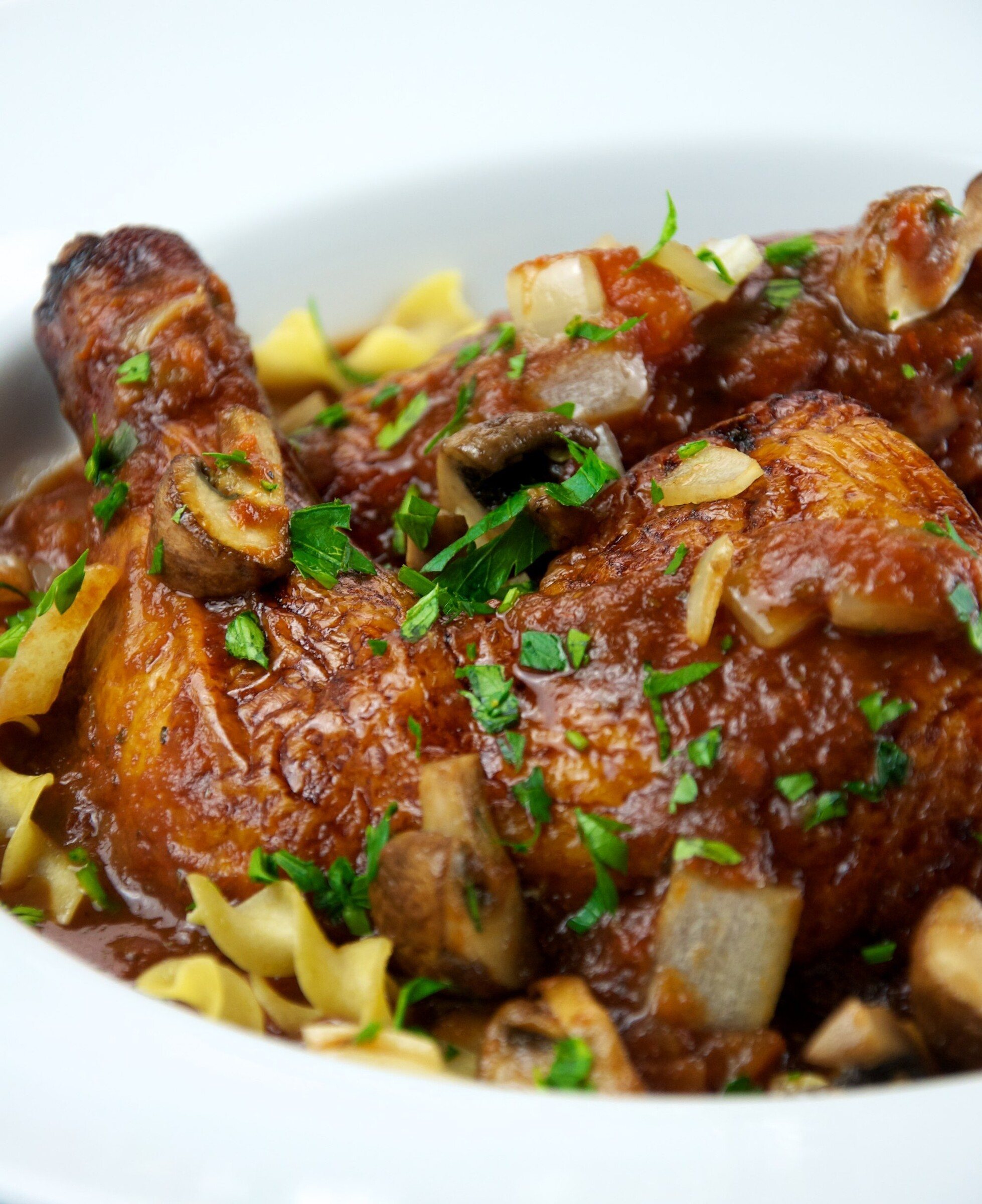 Chicken cacciatore with mushrooms in tomato sauce served over egg noodles