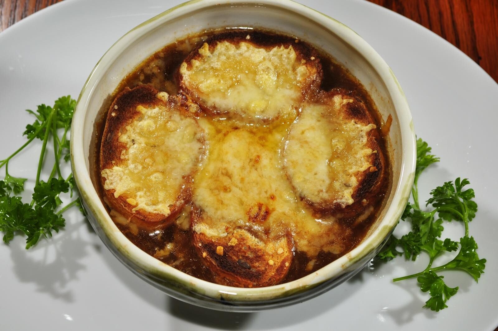 A crock of French onion soup topped with melted, browned cheese