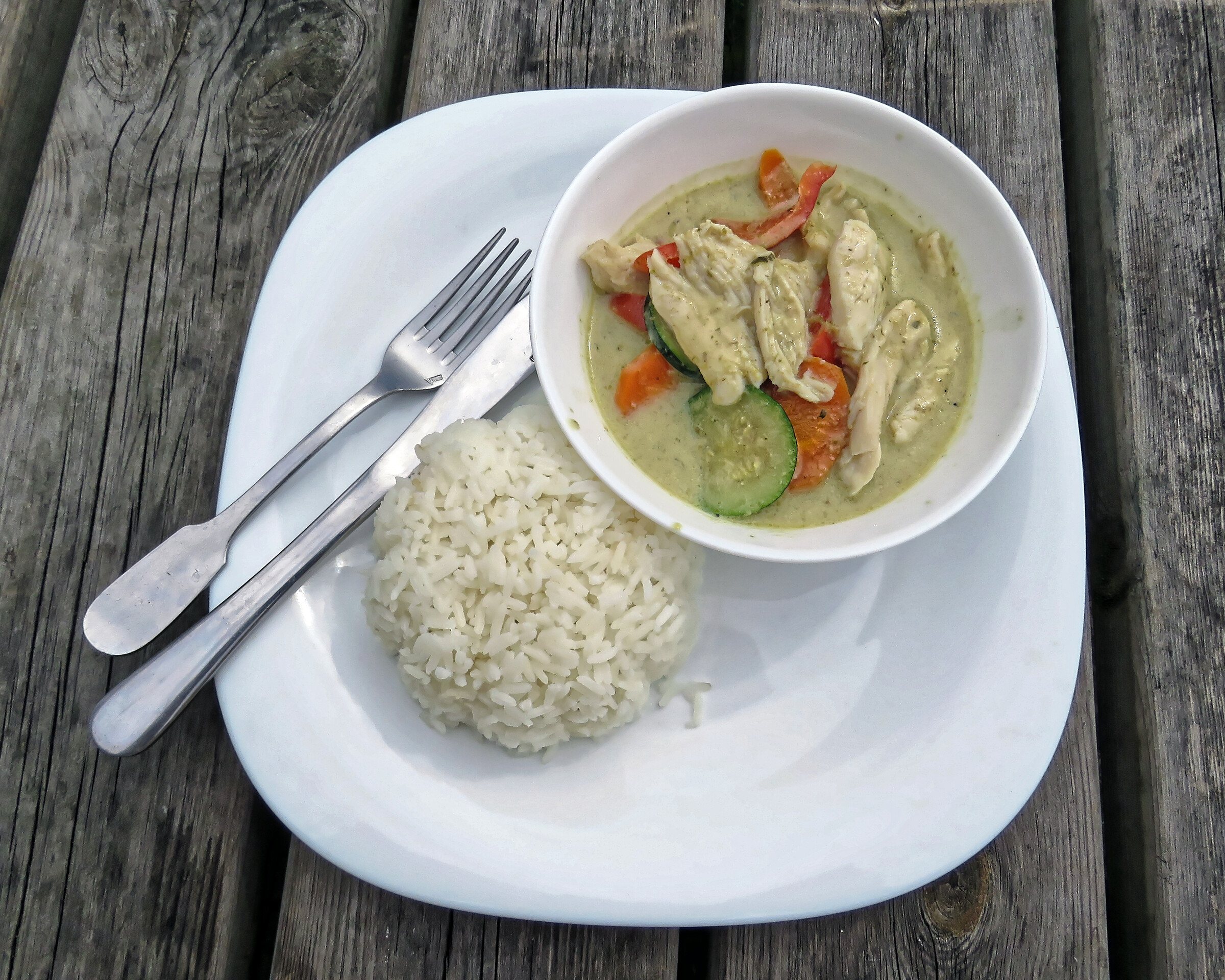A bowl of Thai green chicken curry with a side of white rice