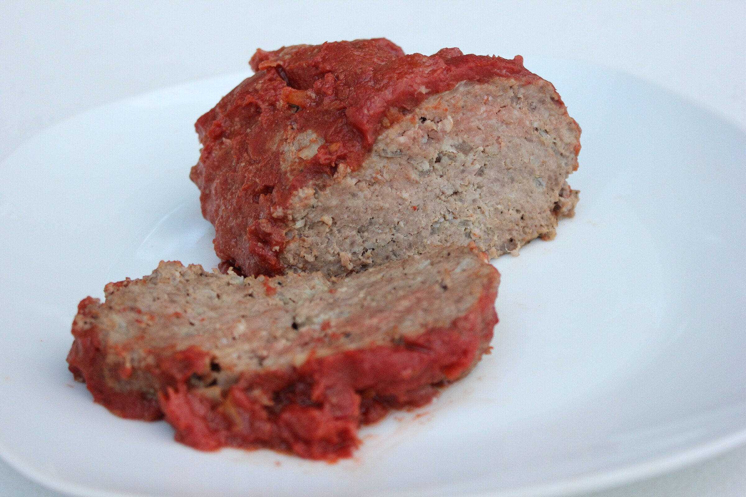 Slices of glazed meatloaf on a white plate